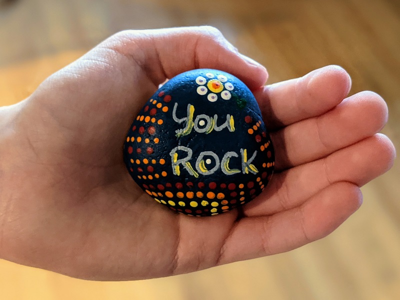 A hand holding a rock with the words "You Rock"
