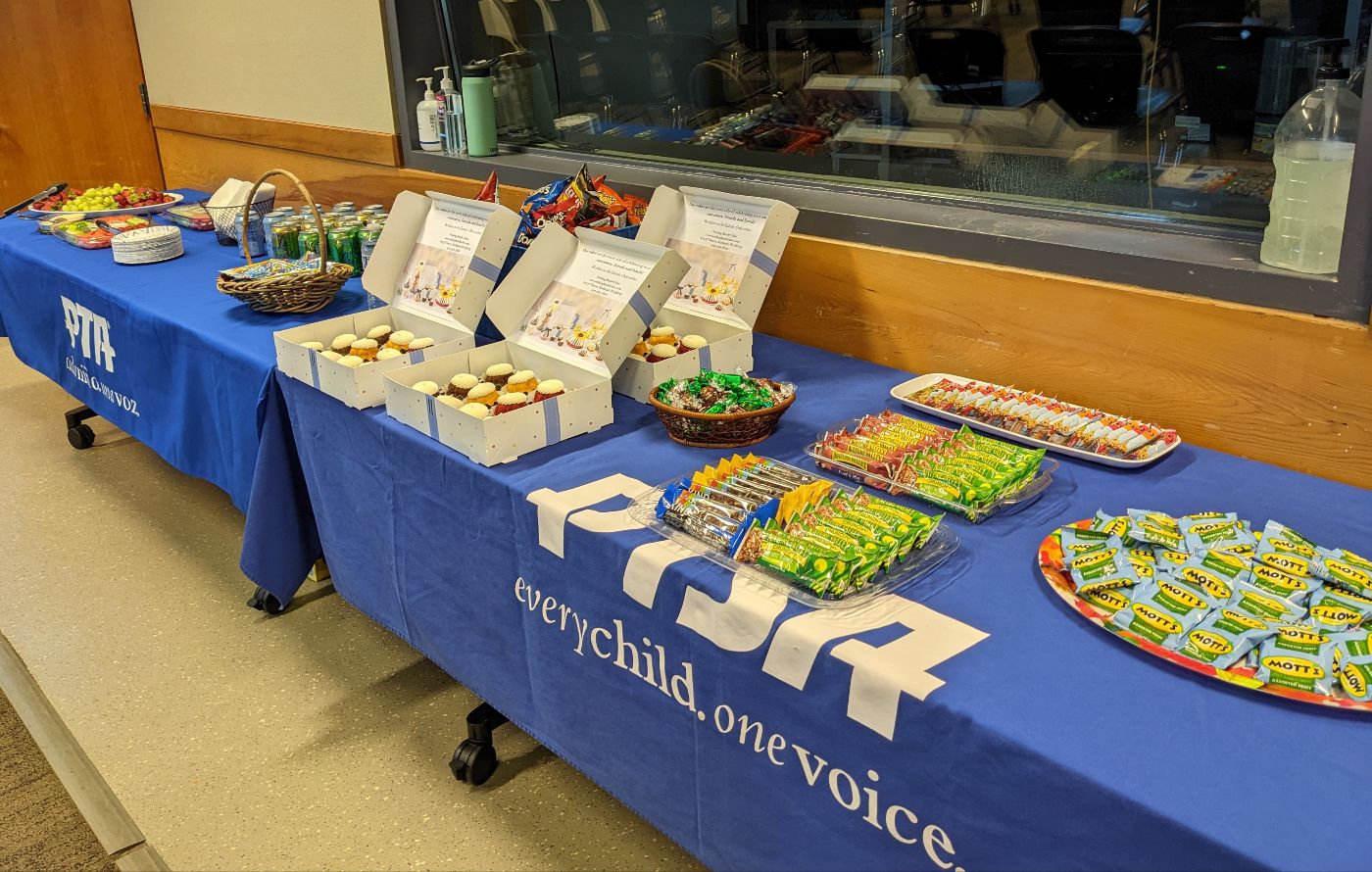 Two tables covered in blue PTSA tablecloths, laid out with an array of snacks.