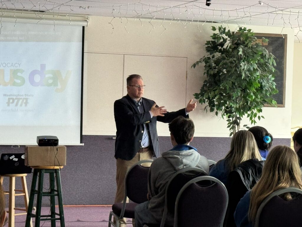 Washington State Superintendent of Public Instruction Chris Reykdal gestures while speaking at the front of a conference room to an audience at Washington State PTA Focus on Advocacy Day, Feb. 17, 2025